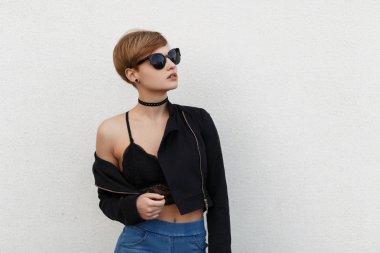 Şık güzel genç model kadın güneş gözlüğü siyah bir ceket ve dantel iç çamaşırı yakınındaki beyaz bir duvar ile