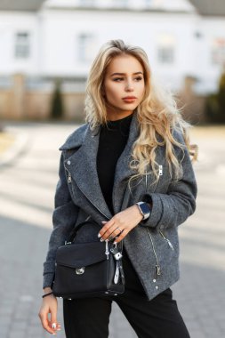 Güneşli bir günde şık bahar paltolu bir şık siyah çanta ile genç modeli kadın moda
