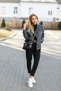 Genç ve güzel kadın moda ceket ile açık havada bahar güneşli bir günde poz beyaz spor ayakkabı