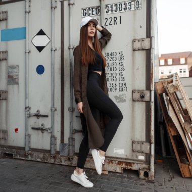 Şık beyaz şapkası ve sokakta teneke bir kutuda yakınındaki poz Ayakkabı Moda ceketle güzel genç kadın