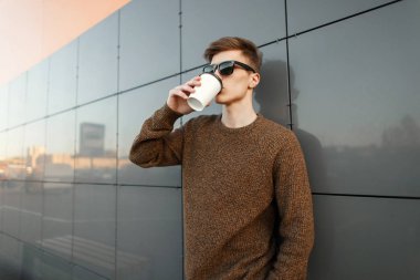 Hipster adam duvar alışveriş merkezi yakınında sokakta kahve içme güneş gözlüğü