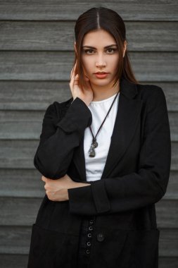 Bir ahşap duvar açık havada yakınındaki şık siyah paltolu güzel model kadın moda portre