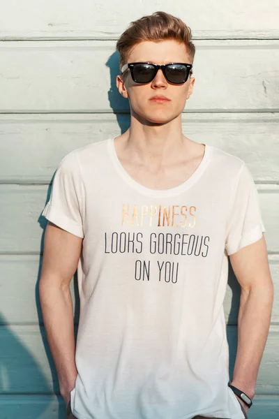 Handsome hipster guy with sunglasses in a white T-shirt and an inscription \
