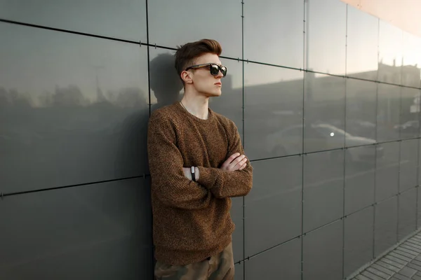 Стильный Молодой Человек Солнечных Очках Модном Пуловере Позирует Возле Современной — стоковое фото