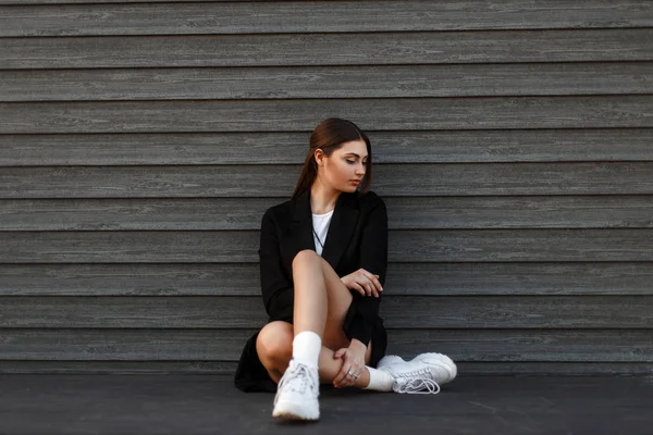 Beautiful Model Woman Fashionable Black Coat White Sneakers Sits Wooden — Stock Photo, Image