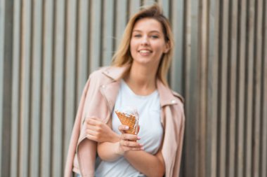 Mutlu genç kadın dondurma yakınındaki bir ahşap duvar ile pembe ceket