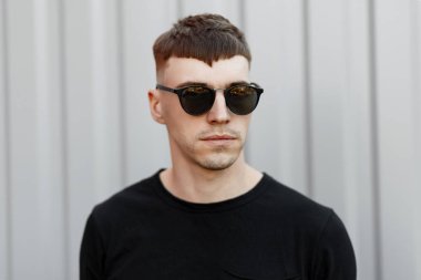 Şık siyah tank top gri duvarının yakınında bir moda gözlüklü genç bir şık adam portresi