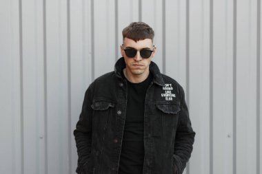 siyah gözlük ve siyah şık denim giyim gri duvarının yakınında bir saç modeli ile genç acımasız kötü adam
