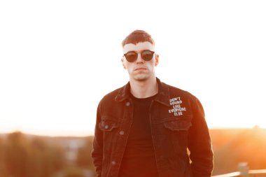 Denim siyah şık elbiseleri günbatımı, bir saç kesimi ile moda acımasız adam. Moda güneş gözlüğü