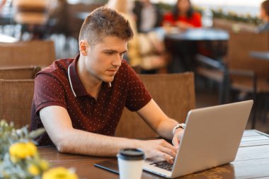 Kafede dizüstü bilgisayarda çalışan genç işadamı.