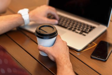 Blogger adam kahve içer ve bir dizüstü bilgisayarda çalışır. Yakın çekim