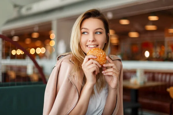 Feliz Hermosa Mujer Joven Comiendo Una Hamburguesa Interior — Foto de Stock