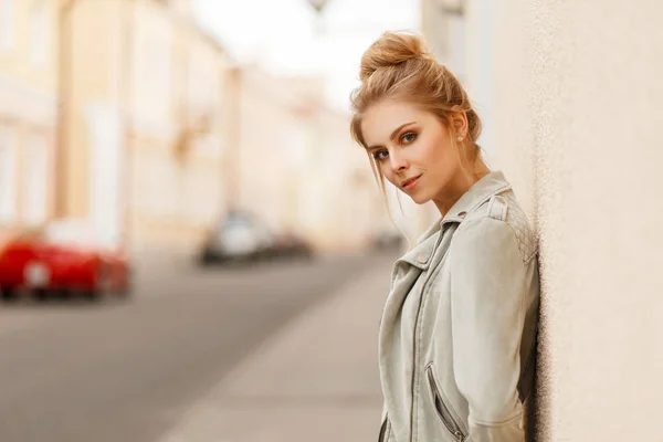都市の壁の近くのファッショナブルなジャケット滞在でスタイリッシュな若い美しい女性 — ストック写真