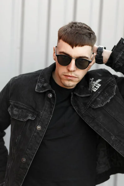 英俊的年轻人美国模型在太阳镜的发型在黑色时尚牛仔服装在街上 — 图库照片