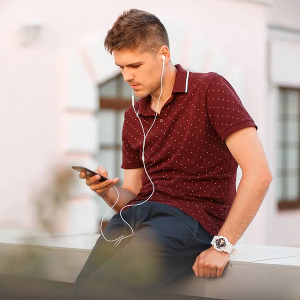 handsome man with a phone and headphones listening to music on the street