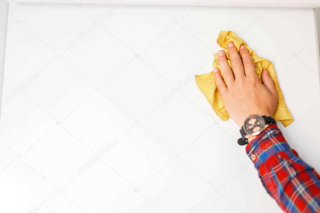 man's hand with a rag is cleaning a white board in the office