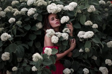 Bir bahçe beyaz çiçeklerle çalılıklarda pembe elbiseli Genç güzel kadın