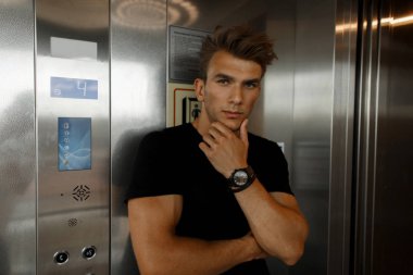 Asansörde siyah T-shirt bir saç modeli ile moda yakışıklı genç adam