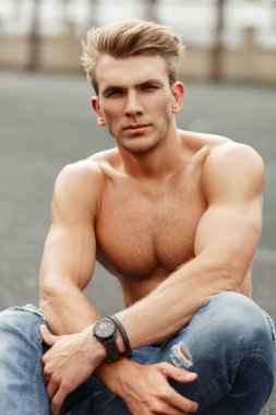 Yakışıklı genç model saç modeli ile asfalt üzerinde sokakta oturan spor vücut ile