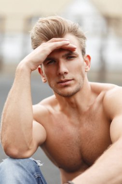 Moda yakışıklı genç adam sokakta oturan bir çıplak spor gövdeli bir saç modeli ile