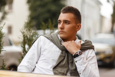 Beyaz bir gömlek şık genç başarılı adam sokakta bir kafede oturuyor