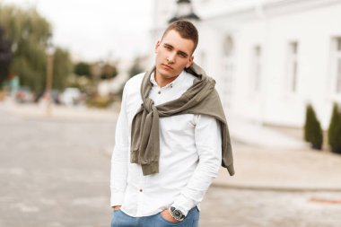 Şık yakışıklı genç Beyaz tişörtlü adam şehirde yürüyüş kazak modeli