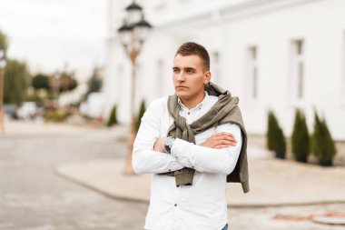 Şehirde poz bir kazak beyaz gömlekli bir saç kesimi ile başarılı delikanlı