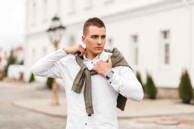 Yakışıklı başarılı delikanlı şehirde poz bir kazak ile beyaz bir gömlek