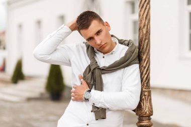 Genç yakışıklı modeli adam sokakta bir kazak beyaz gömlekli bir saç kesimi ile