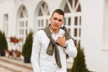 Moda yakışıklı genç işadamı adam beyaz gömlek ve şehirde yürüyüş kazak