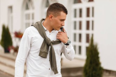 Şık genç yakışıklı bir saç kesimi Beyaz gömlekli adam şehirde yürüyüş bir kazak modeli