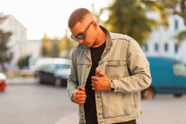 Yakışıklı delikanlı sokak güneşli bir günde bir kot moda ceket içinde güneş gözlüğü ile şık bir saç modeli ile