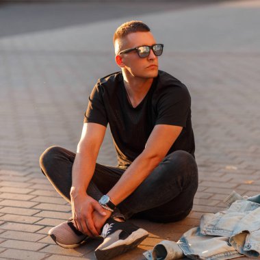 Moda yakışıklı genç modeli içinde sokakta oturan siyah şık T-shirt Siyah güneş gözlüğü