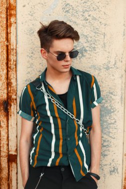 Paslı bir duvar şık yakışıklı genç hipster adam güneş koruyucu gözlük ile şık bir gömlek ile standları