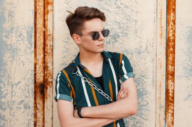 paslı metal duvar yakınındaki bir plaj parlak gömlekli şık gözlüklü genç adam