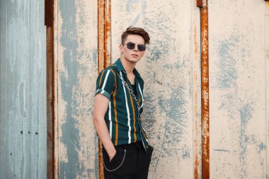 Genç yakışıklı olan metal duvarın yanında şık plaj yeşil gömlekli moda güneş gözlüğü ile