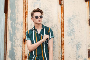 Plaj moda gömlek metal duvar poz bir çanta ile şık bardaklarda yakışıklı genç