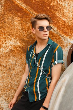 Sokakta bir paslı duvarının yakınında bir parlak renkli plaj gömlekli gözlüklü şık yakışıklı adam