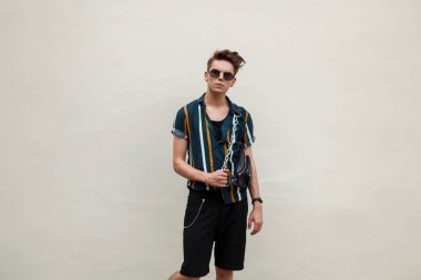 Yeşil duvarın yanında bir çanta çizgili bir plaj gömlekli bir saç modeli olan modeli yakışıklı adam