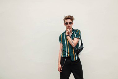 Yeşil duvara yakın poz çanta ile plaj renkli gömlekli gözlüklü şık genç yakışıklı adam