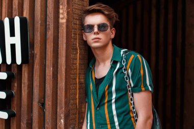 ahşap duvar yakınındaki plaj gömlekli gözlüklü genç yakışıklı şık adam