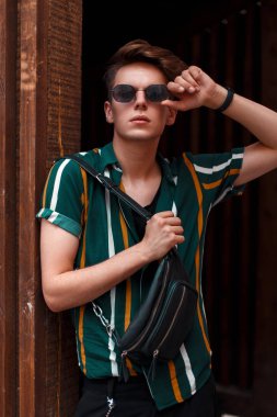 ahşap duvarının yakınında şık bir gömlek şık güneş gözlüğü ile yakışıklı genç