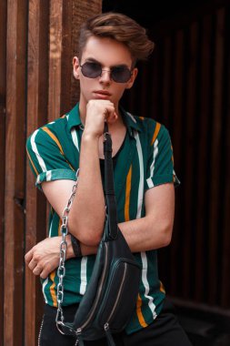 Şık genç yakışıklı bir ahşap duvar yakınında bir sokakta bir yaz gömlek