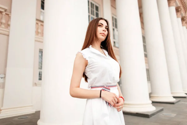 美丽的年轻女子在时髦的白色礼服附近的老式专栏 — 图库照片