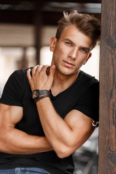 Moda yakışıklı genç adam sokakta siyah T-shirt bir saç modeli ile