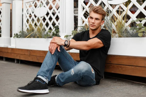 Kot pantolon ve ayakkabı sahilde oturan siyah tişört şık yakışıklı genç adam