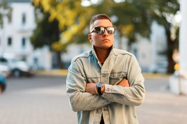 Fashionable hipster man with a haircut in a jeans jacket in the street