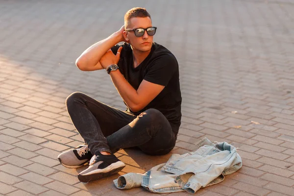 yakışıklı genç adam sokakta oturan bir kot ceket ile siyah şık giysiler içinde