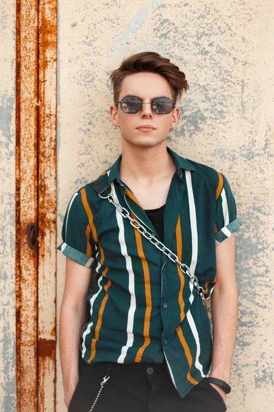 Şık genç yakışıklı bir metal duvar poz trendy beach gömlekli şık güneş gözlüğü