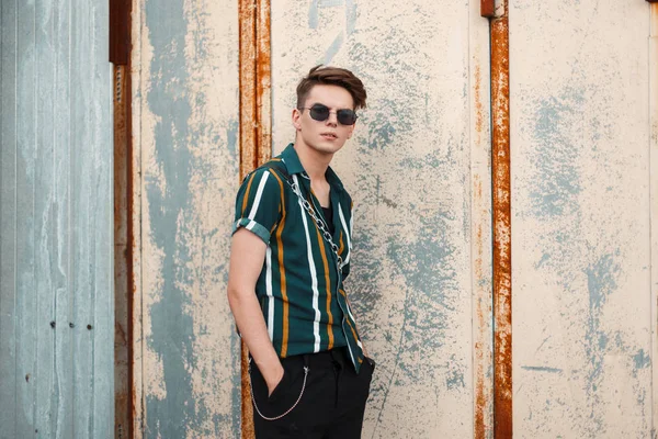 Genç yakışıklı olan metal duvarın yanında şık plaj yeşil gömlekli moda güneş gözlüğü ile